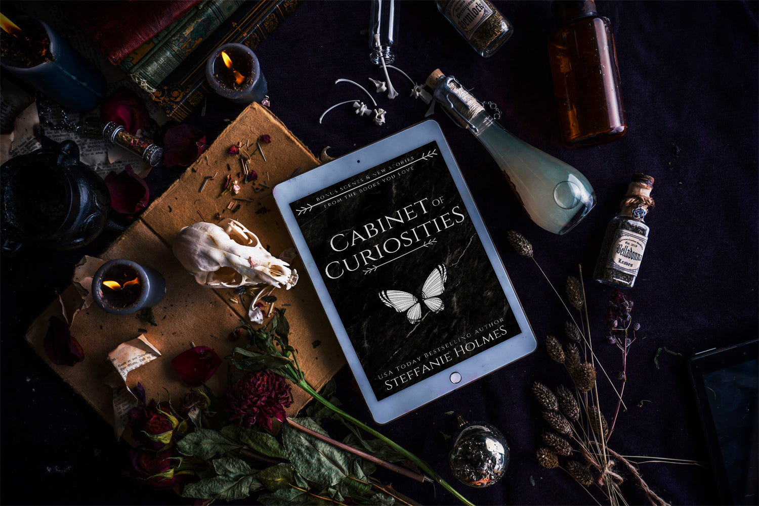 'Cabinet of Curiosities' by Steffanie Holmes ebook cover on tablet, on a table with various witchy and occult objects