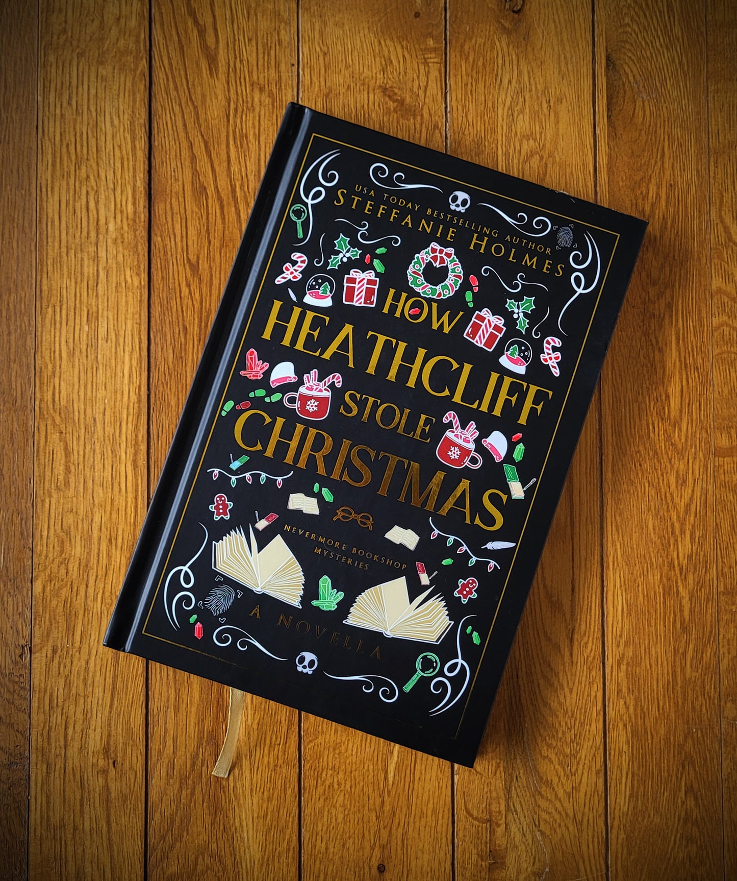 A hardcover book titled 'How Heathcliff Stole Christmas' displayed on a wooden surface, featuring a decorative, vintage-style cover design with Christmas-themed illustrations.