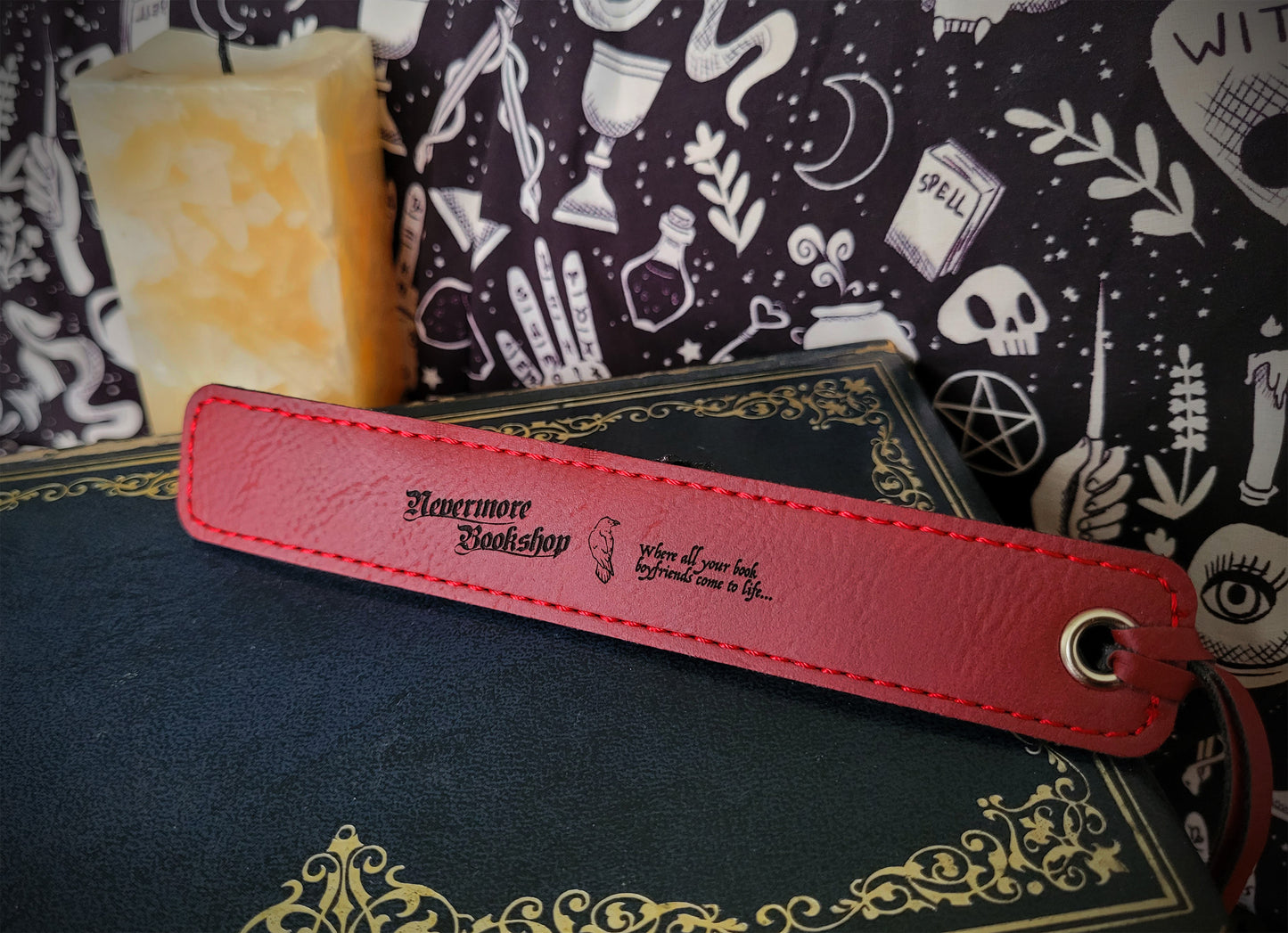a red leatherette bookmark featuring the Nevermore Bookshop logo, a raven and 'WHERE ALL YOUR BOOK BOYFRIENDS COME TO LIFE' inscription