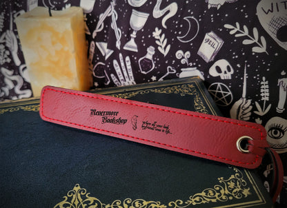 a red leatherette bookmark featuring the Nevermore Bookshop logo, a raven and 'WHERE ALL YOUR BOOK BOYFRIENDS COME TO LIFE' inscription