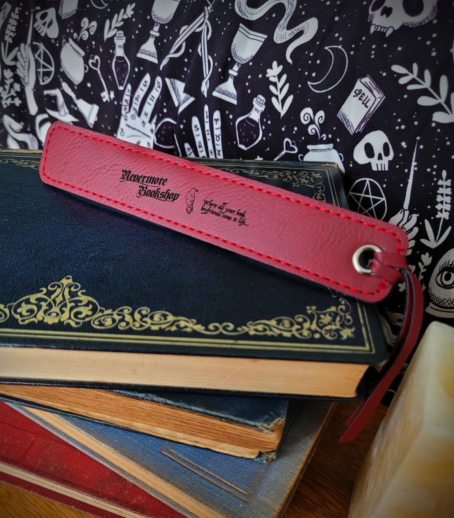 a red leatherette bookmark featuring the Nevermore Bookshop logo, a raven and 'WHERE ALL YOUR BOOK BOYFRIENDS COME TO LIFE' inscription
